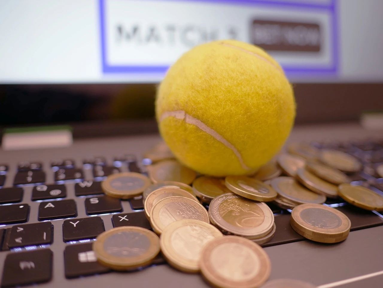 Tennisball og mynter ved en bærbar datamaskin